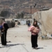 Syrian refugee women carry children as they walk at an informal camp, in the Bekaa Valley, Lebanon October 18, 2022. REUTERS/Mohamed Azakir