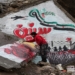 TOPSHOT - A man draws a slogan in Arabic reading "we still want freedom" as part of a graffiti mural commemorating the ninth anniversary of uprising that led to the Syrian conflict (March 15), showing a dove holding an olive branch in its beak flying over a Syrian opposition flag in the shape of the eastern Arabic numeral "9" while being targeted by the silhouette of a military aircraft with the Arabic word "years" below as silhouettes of children stand by a border fence and a tent with the letters "UN", drawn on the collapsed roof of a heavily damaged building in the town of Binnish in the northwestern Idlib province on March 13, 2020. (Photo by Omar HAJ KADOUR / AFP) (Photo by OMAR HAJ KADOUR/AFP via Getty Images)